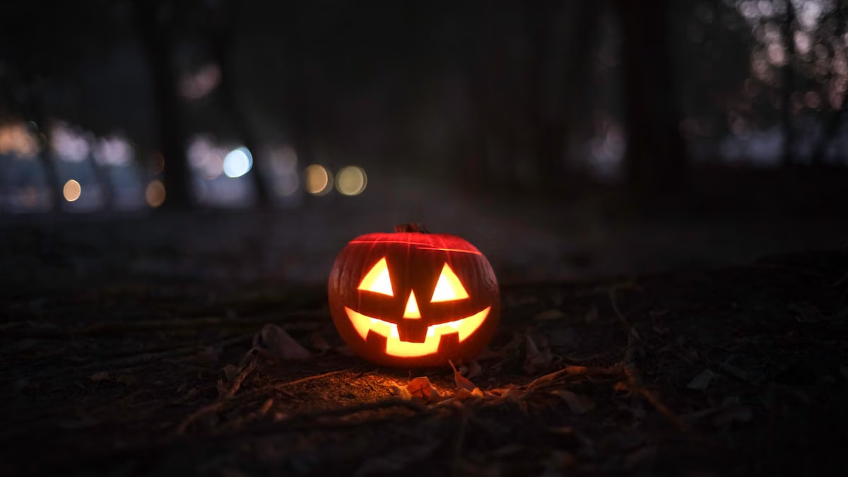 A spooky Jack-O'-Lantern emits an eerie glow in a dark forest, perfect for Halloween.